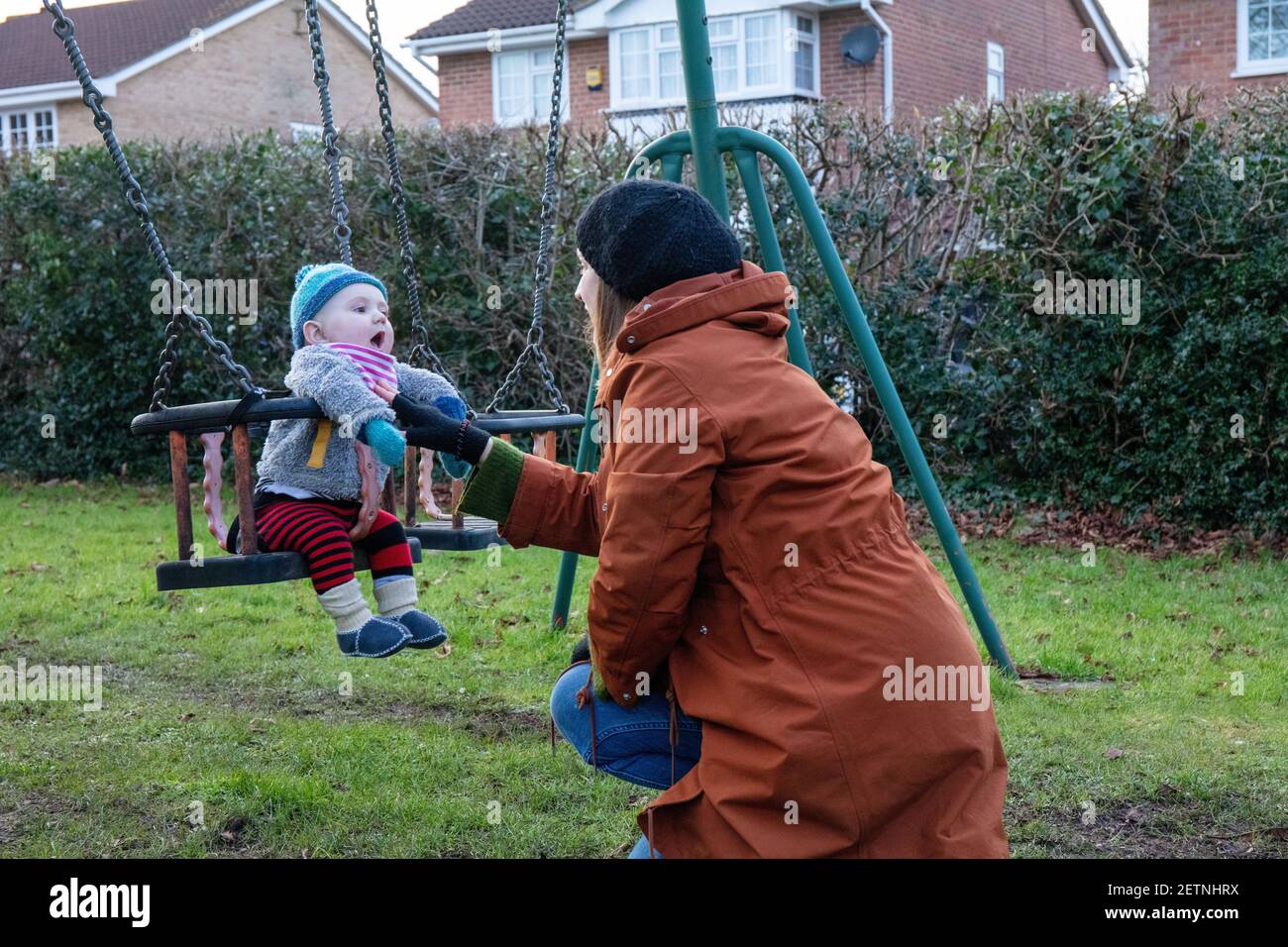 Bébé caucasien sur l'oscillation avec la mère en hiver. Banque D'Images