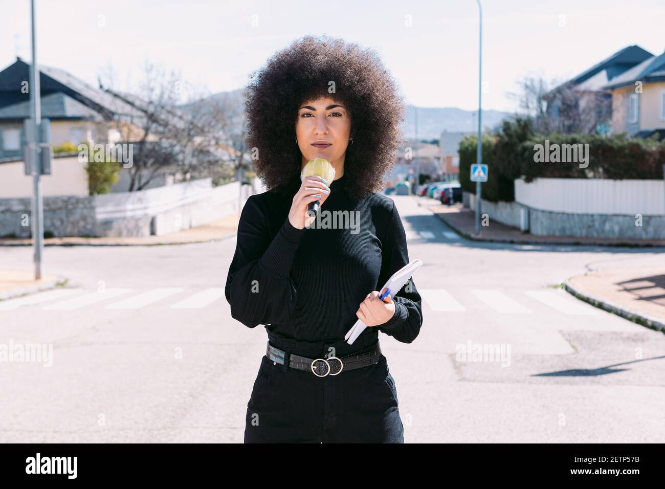 Journaliste de télévision féminine avec afro Hair reportage sur a nouvelles dans la rue Banque D'Images