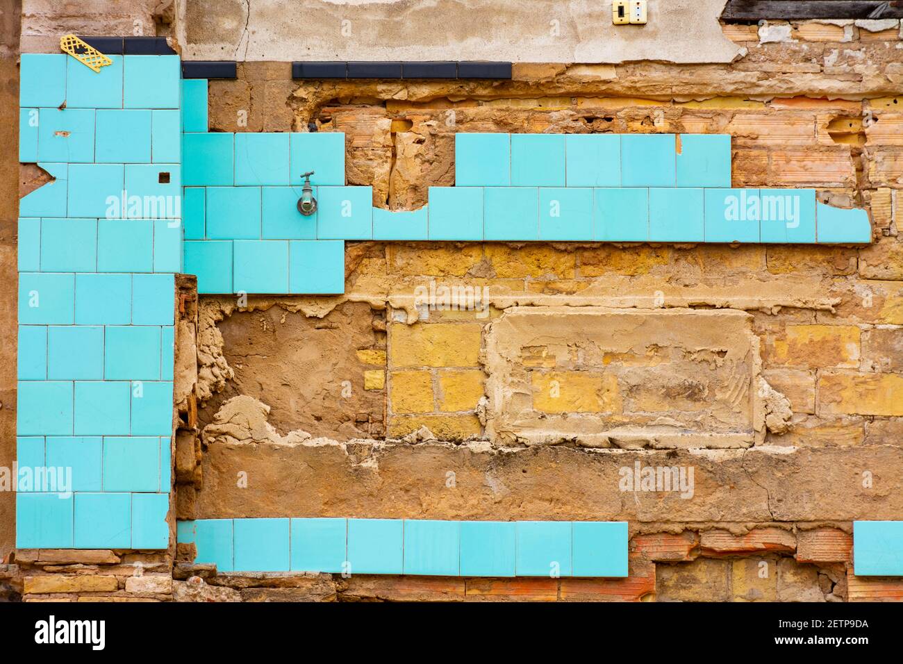 Vestiges du mur intérieur d'une maison dans un bâtiment en ruines, avec des morceaux de carreaux bleus et des parties du mur brut Banque D'Images