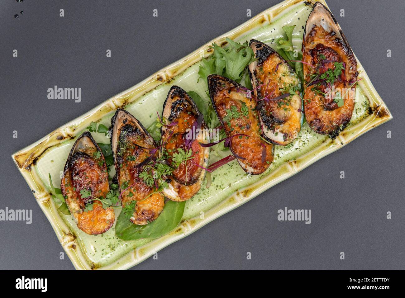 Vue en hauteur de l'apéritif de moules cuites dans une délicieuse sauce avec une belle présentation sur une assiette en bambou. Banque D'Images