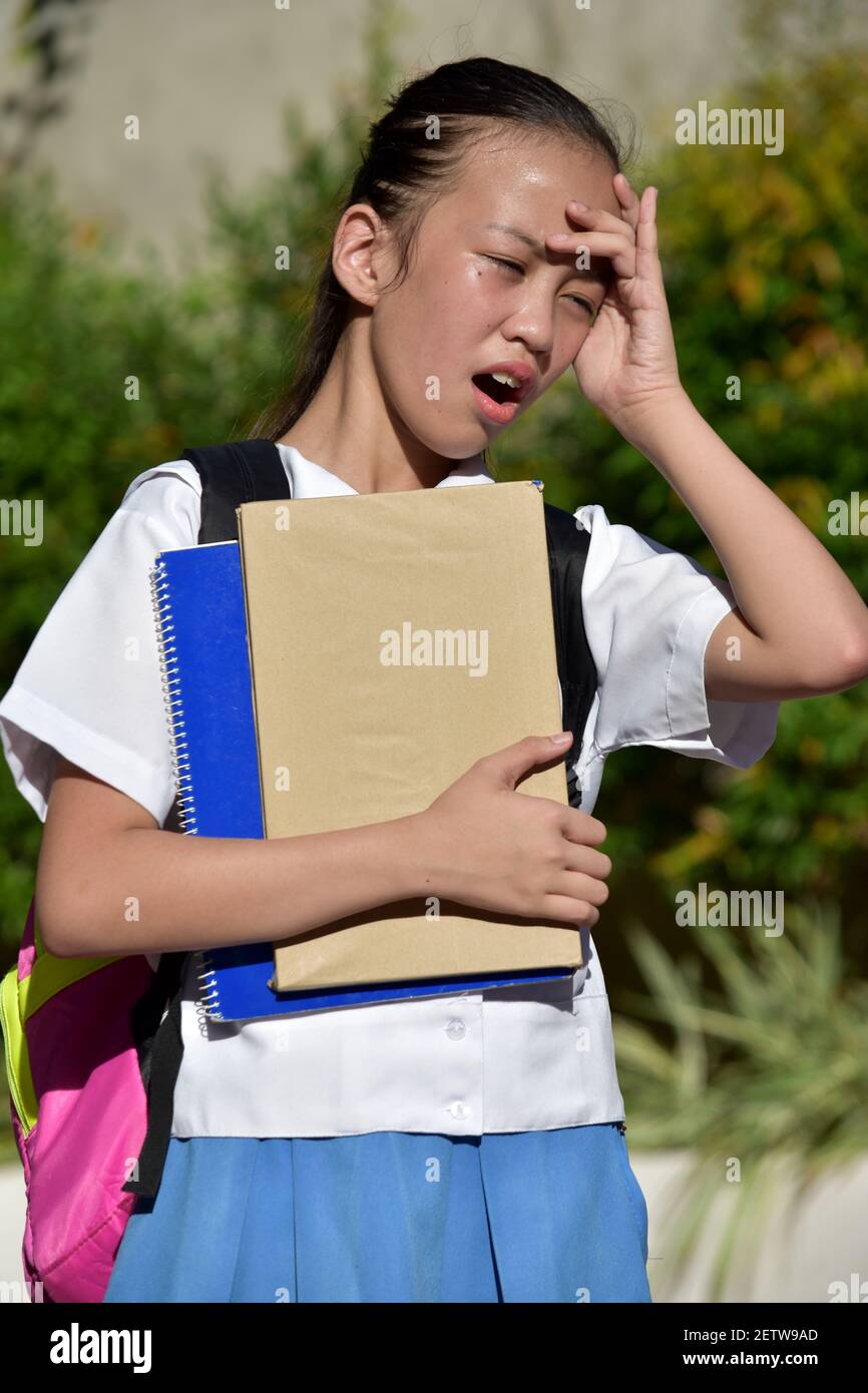 Fille d'école avec mal de tête portant uniforme d'école avec des livres Banque D'Images