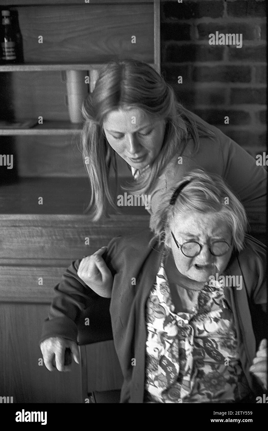 Fille d'école de seize ans en expérience de travail comme assistante de soins dans un foyer de soins. Aider les femmes âgées résidentes à la chaise Banque D'Images