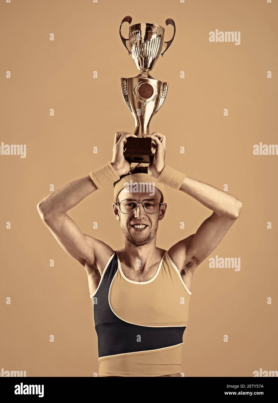 Le gagnant heureux appuie la coupe du prix sur fond jaune. Banque D'Images