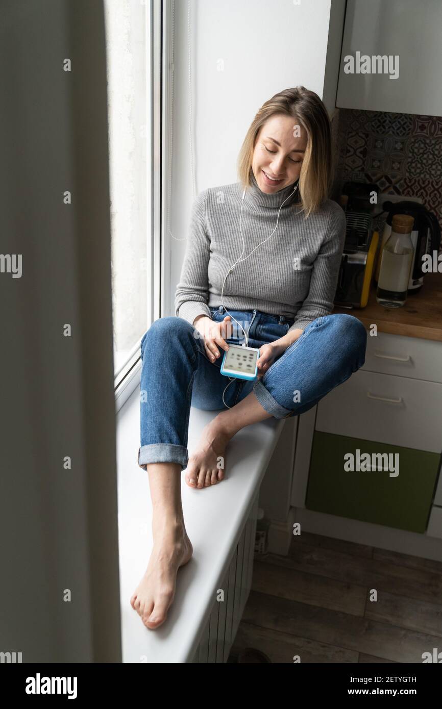 Femme souriante porter un casque à l'aide d'un téléphone mobile parlant, écoutant un podcast ou un club House. Banque D'Images