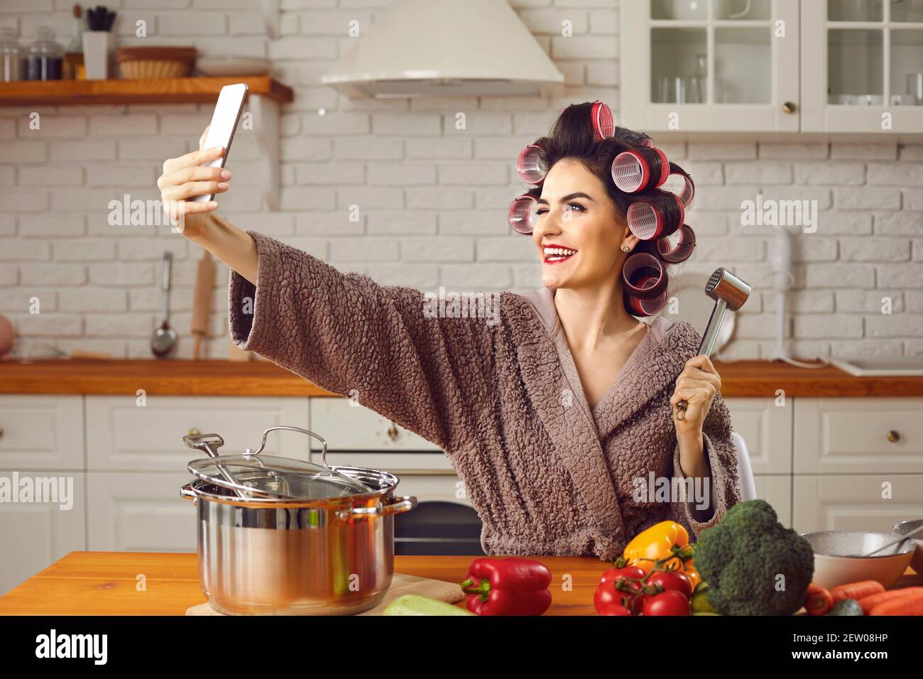 Jeune femme gaie essayant une nouvelle recette et de prendre un un selfie drôle dans la cuisine Banque D'Images