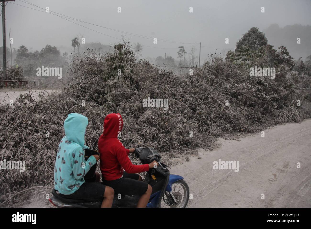Sumatra Nord. 2 mars 2021. Photo prise le 2 mars 2021 montre des gens qui  font de leur moto sur une route couverte de cendre bouée par le mont  Sinabung à Karo,