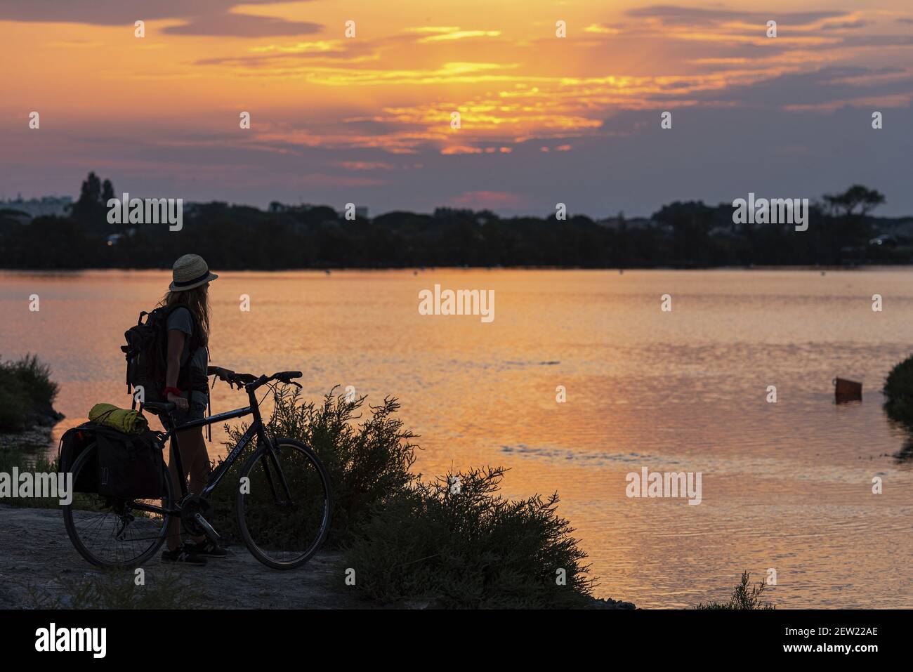 France, Gard (30), Aigues-mortes, jeune femme contemplant le coucher de soleil devant l'Etang du Médard Banque D'Images