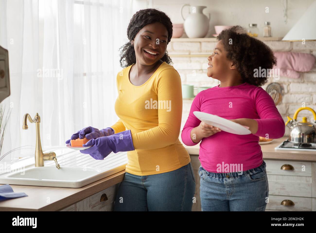 Main d'aide. Mignon petite fille noire aide sa maman dans la cuisine Banque D'Images