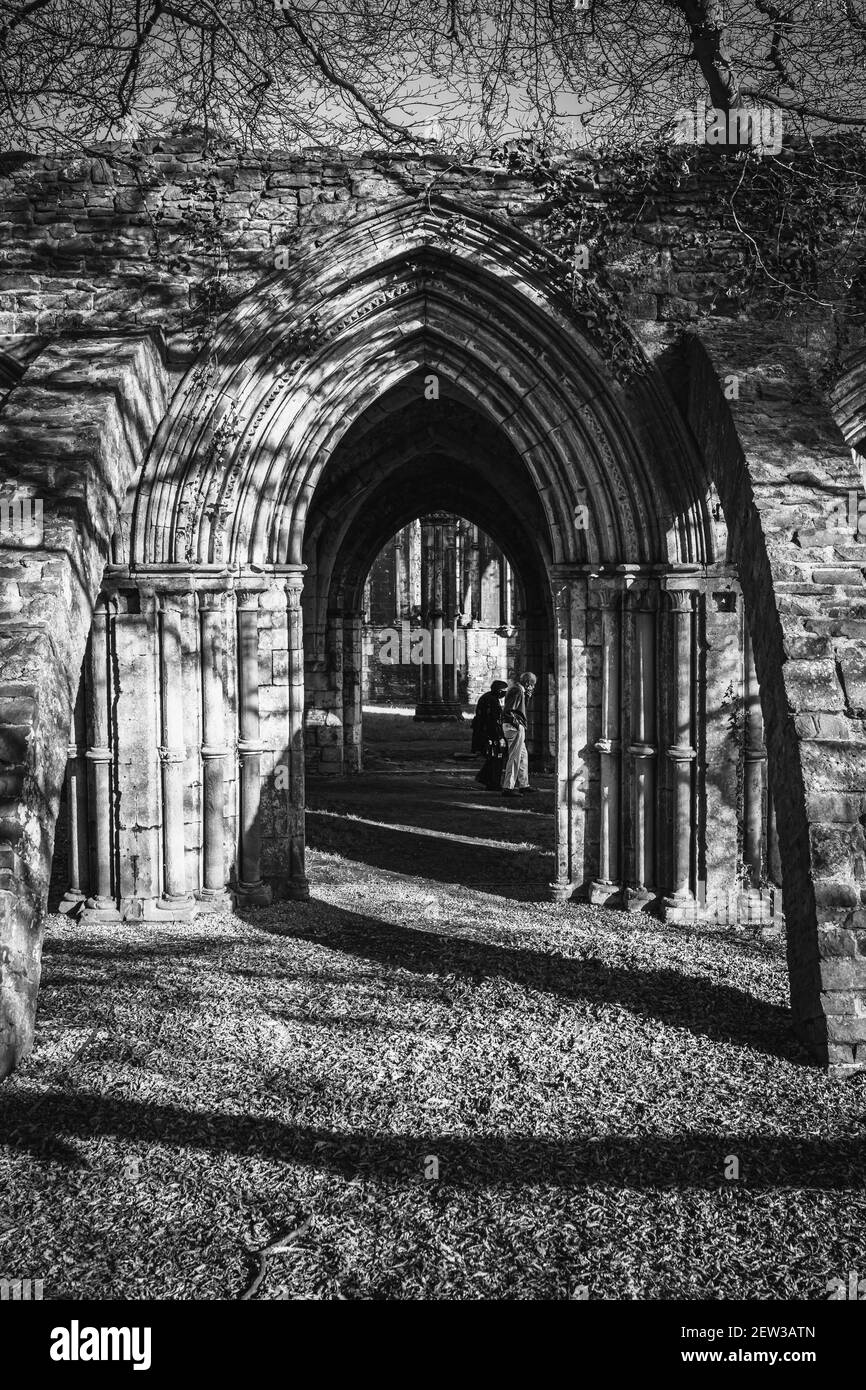 Couple de personnes âgées dans des masques de visage marchant dans le parc national de Margam, les ruines de l'abbaye, le sud du pays de Galles. Noir et blanc Banque D'Images
