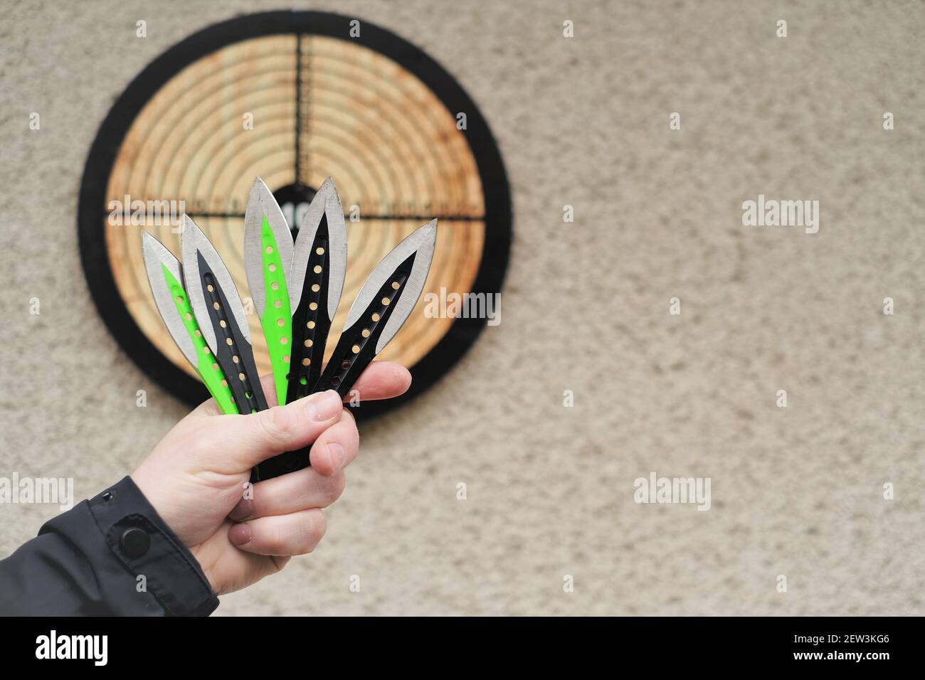 Projection de couteaux. Sport et passe-temps . Lancer des couteaux dans la main d'un homme de près et une cible sur le mur.Sports de plein air. Concept de réalisation des objectifs. Banque D'Images