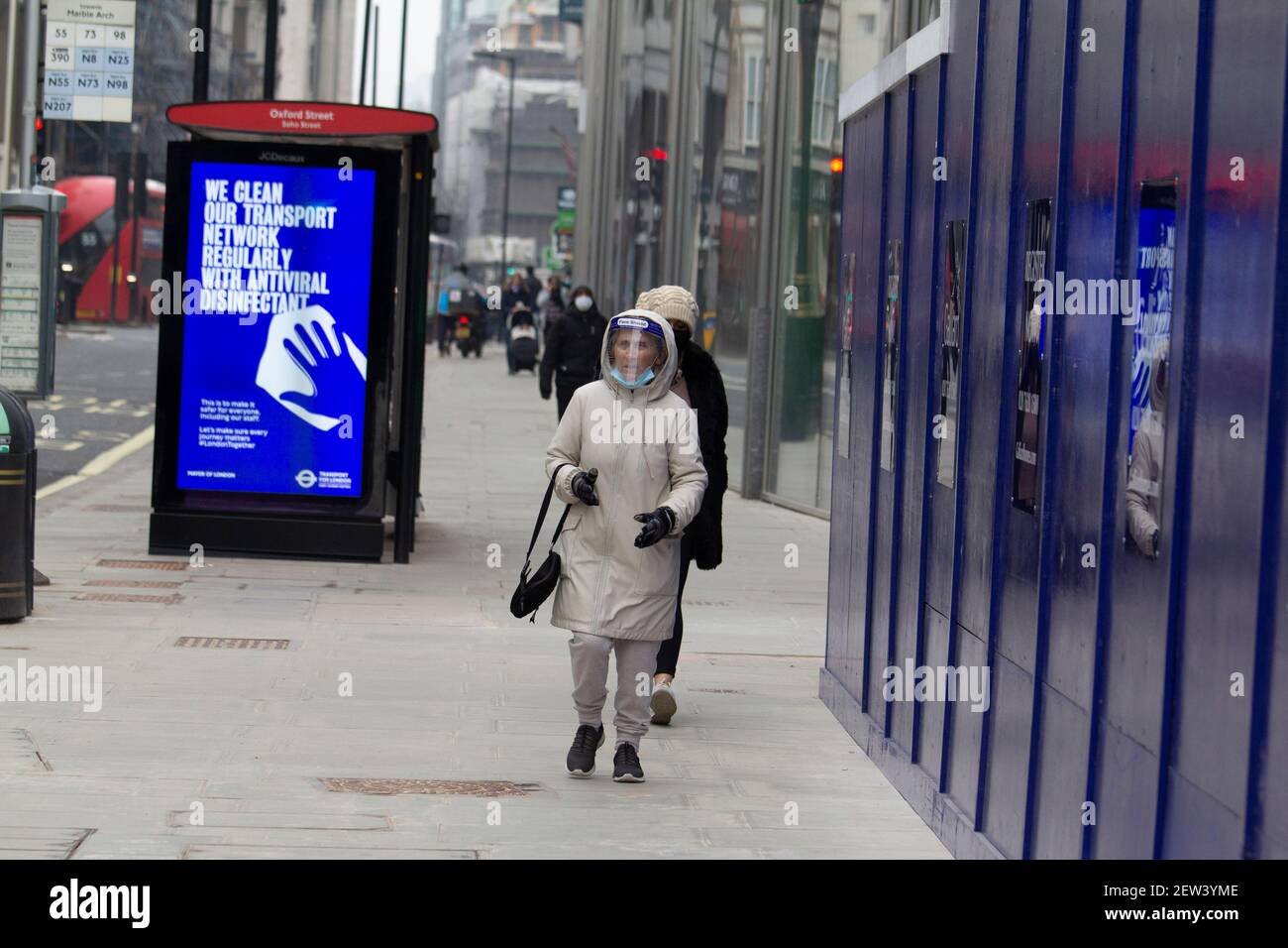 Oxford Street London, pendant le confinement de la pandémie Covid-19 du coronavirus, une femme portant un masque de protection individuelle passe devant l'affiche d'information Covid Banque D'Images