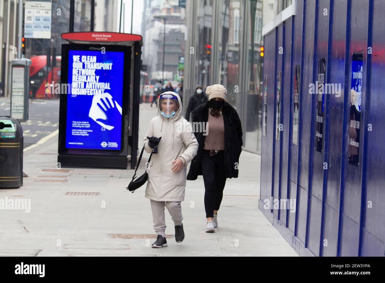 Oxford Street London, pendant le confinement de la pandémie Covid-19 du coronavirus, une femme portant un masque de protection individuelle passe devant l'affiche d'information Covid Banque D'Images