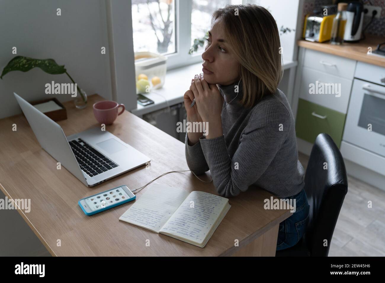 Une femme porte un casque, en utilisant un smartphone, écoute attentivement un haut-parleur intéressant dans le pavillon. Banque D'Images