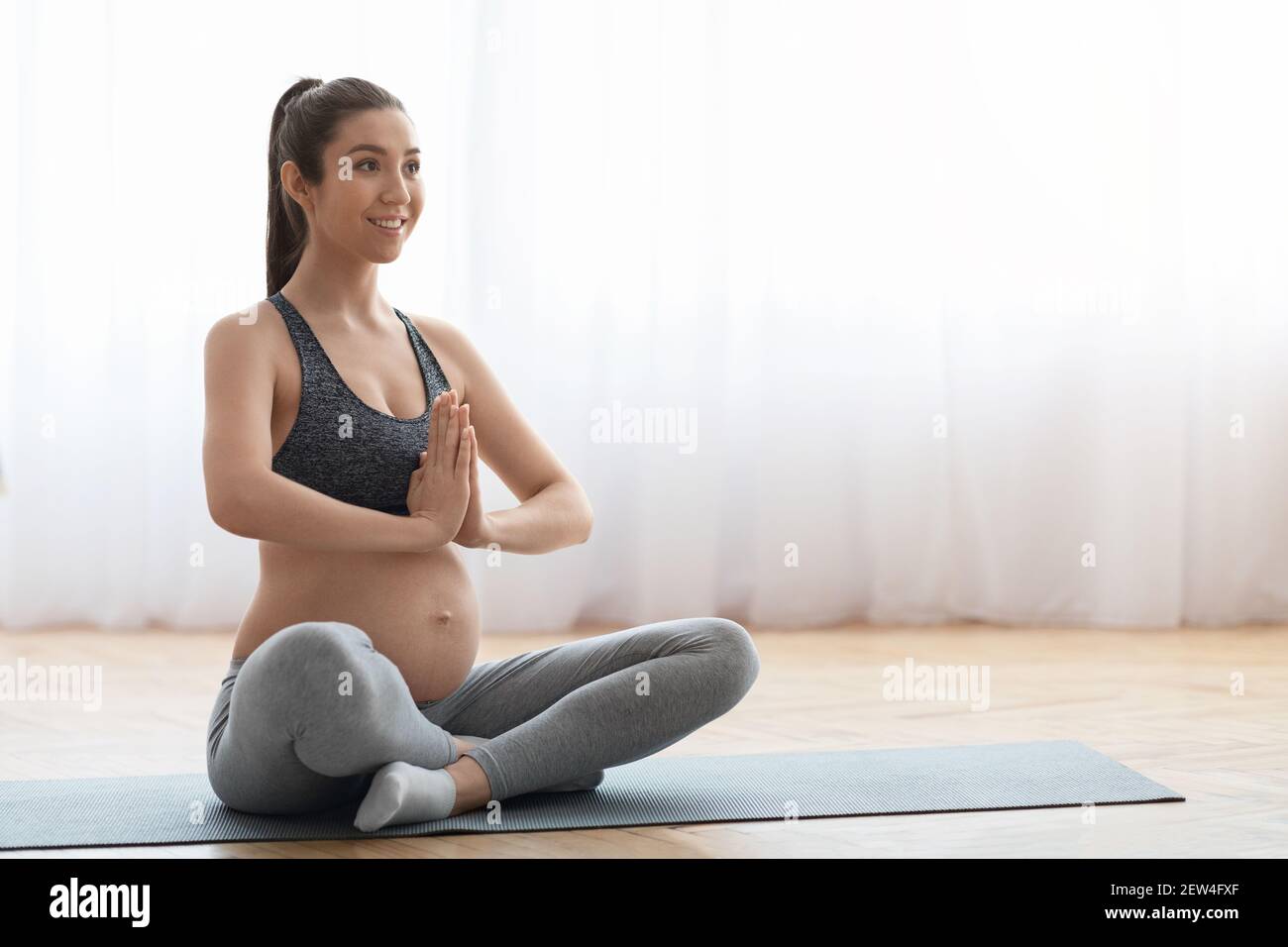 Grossesse Yoga. Femme enceinte millénaire pratiquant des méditations en position lotus à la maison Banque D'Images