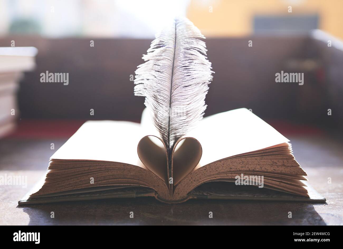 Livre Ouvert Avec Des Pages Pliees En Forme De A Coeur Et Une Plume Entre Eux Sur Une Table En Bois Photo Stock Alamy