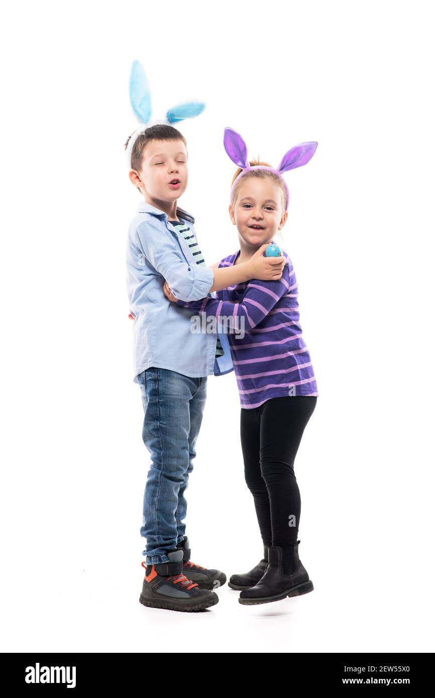 Adorable garçon et fille avec des oreilles de lapin de Pâques chantant et s'amusant célébrant Pâques. Corps entier isolé sur fond blanc. Banque D'Images