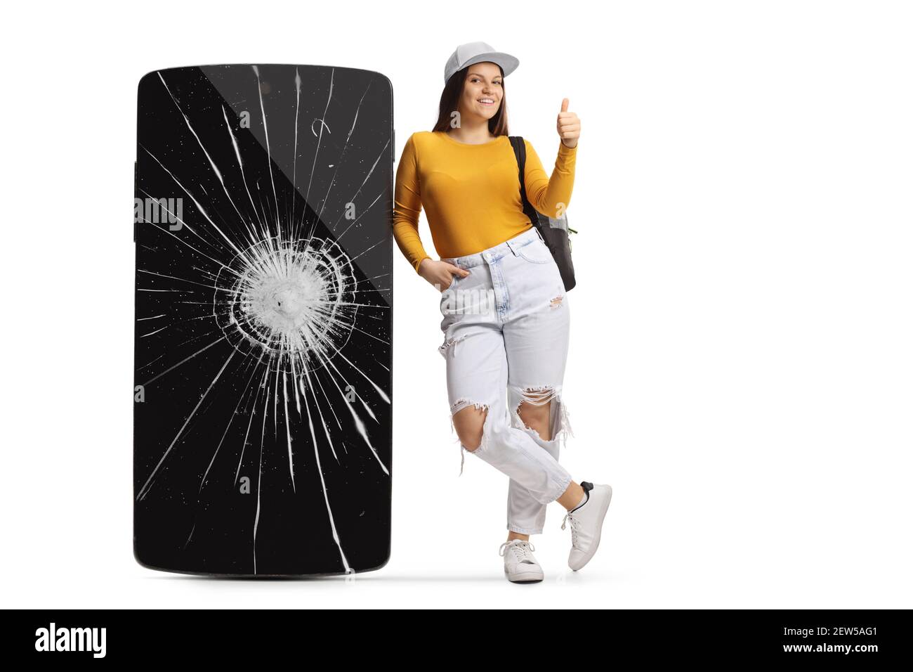 Portrait complet d'une étudiante de sexe féminin penchée sur un téléphone portable avec écran fissuré et pouce vers le haut isolé sur fond blanc Banque D'Images