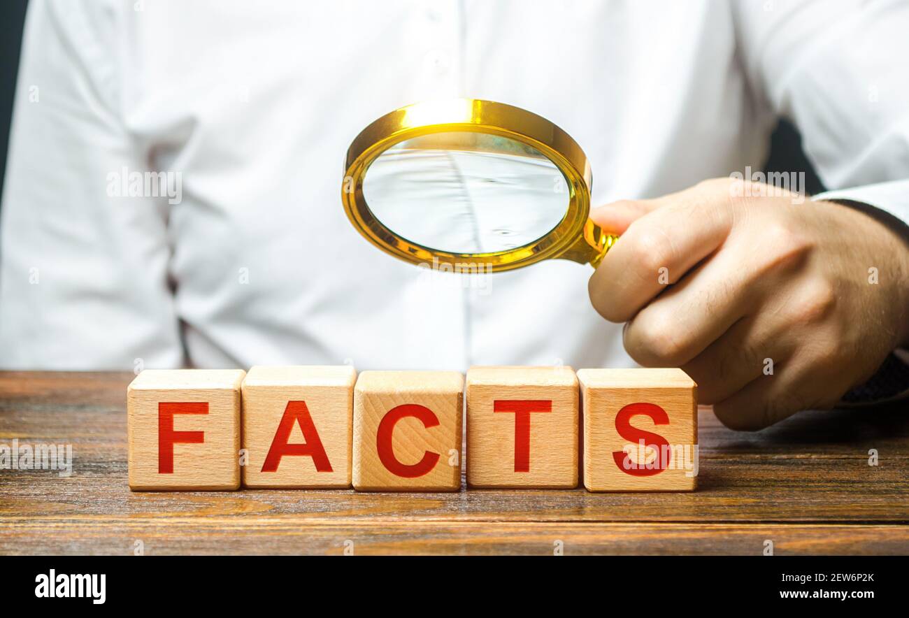 L'homme examine les blocs avec des faits de mot avec une loupe. Vérification de la plausibilité des faits et des données. Démystifier les fakes et contrer la propagande. Con Banque D'Images