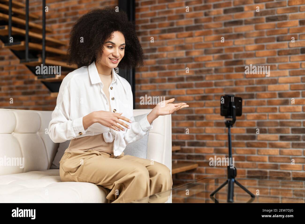 Jeune femme afro-américaine élégante experte blogueuse avec la coiffure  afro streaming vidéo en ligne, enregistrement tutoriel pour les médias  sociaux, en direct, parler avec des suiveurs, regarder le téléphone sur un  trépied