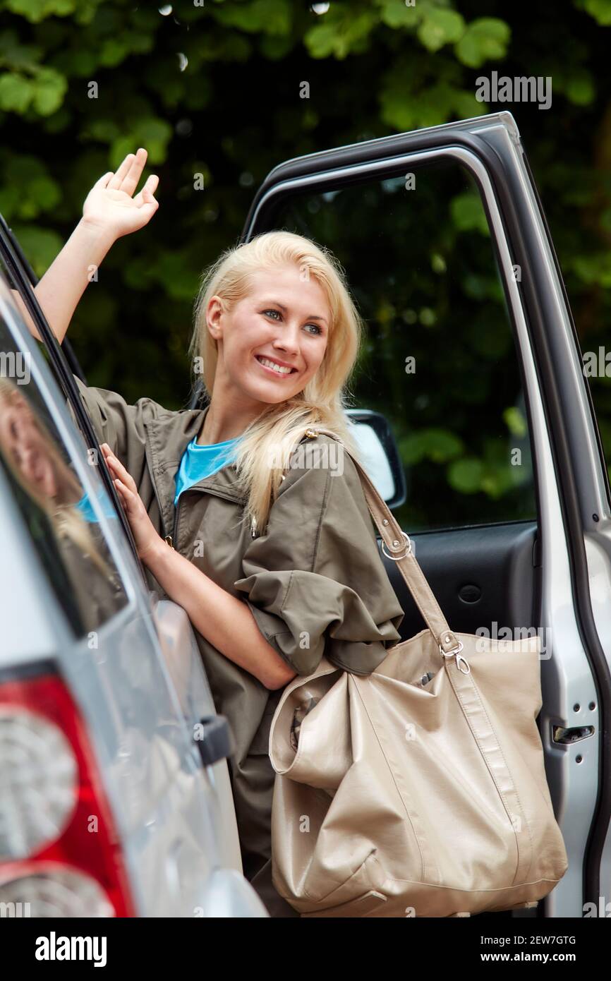 Belle fille avec un sac entrant dans sa voiture Banque D'Images