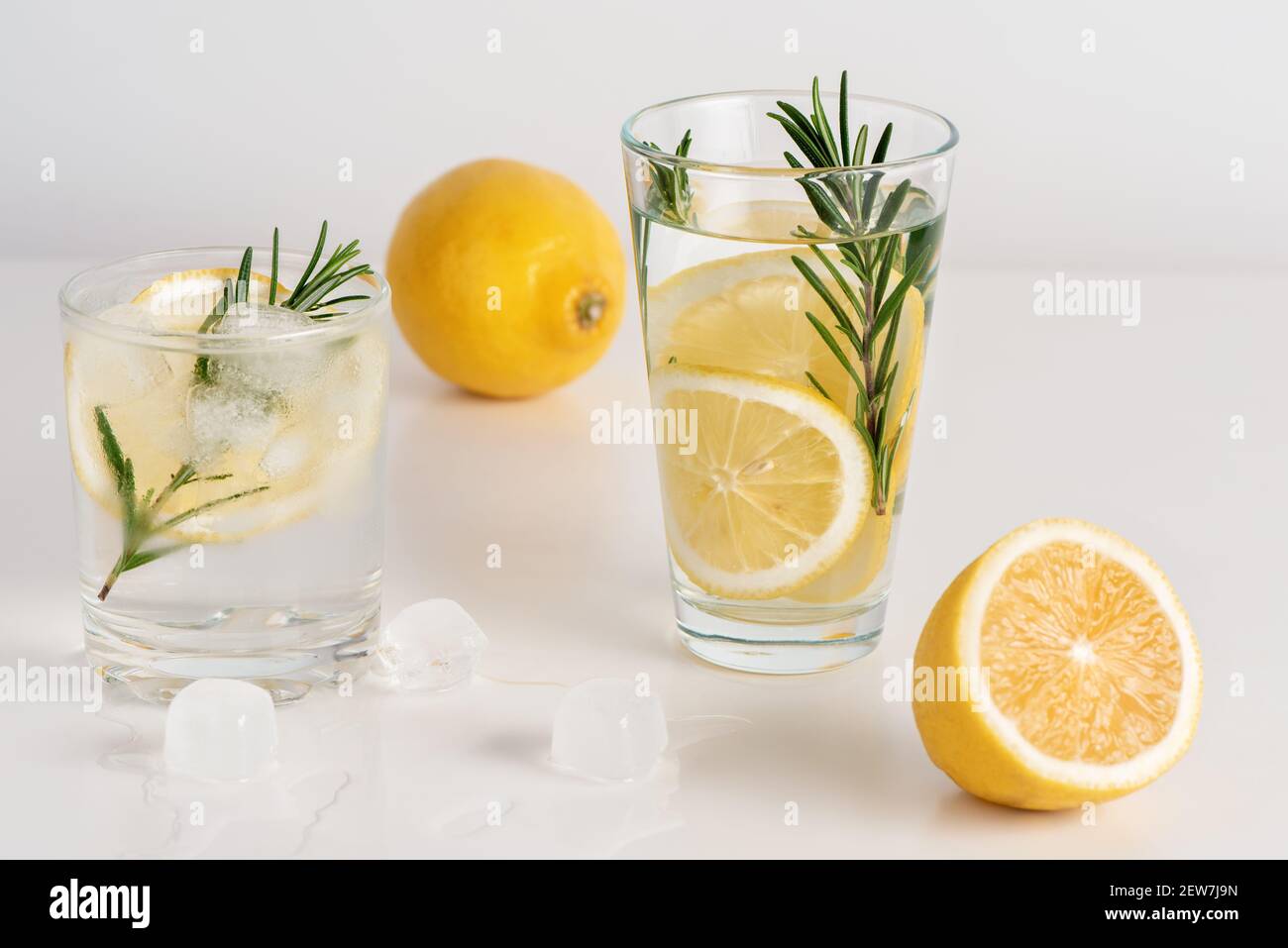 Deux verres d'eau avec des tranches de citron, du romarin et de la glace. Banque D'Images