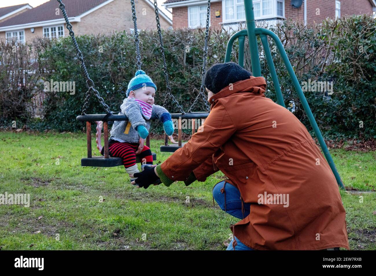 Bébé caucasien sur l'oscillation avec la mère en hiver. Banque D'Images