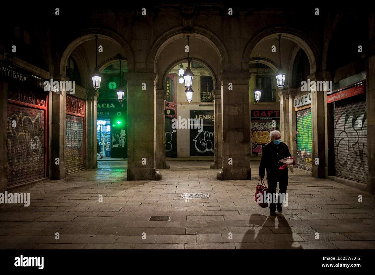 Un homme portant un masque facial tient de petits vêtements à vendre aux passants et obtient de l'argent sur la place Plaza Real de Barcelone où les bars et les restaurants restent fermés le soir dans le cadre des restrictions de pandémie de coronavirus. La troisième vague du coronavirus fait apparaître en Espagne un chômage supérieur à quatre millions. Banque D'Images