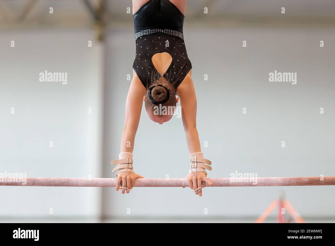 Une fille de vêtements de sport effectue un exercice sur les barres inégales. Gymnastique rythmique, entraînement dans le hall. Banque D'Images