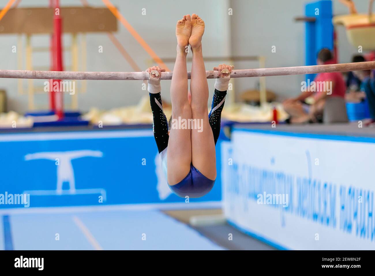Une fille de vêtements de sport effectue un exercice sur les barres inégales. Gymnastique rythmique, entraînement dans le hall. Banque D'Images