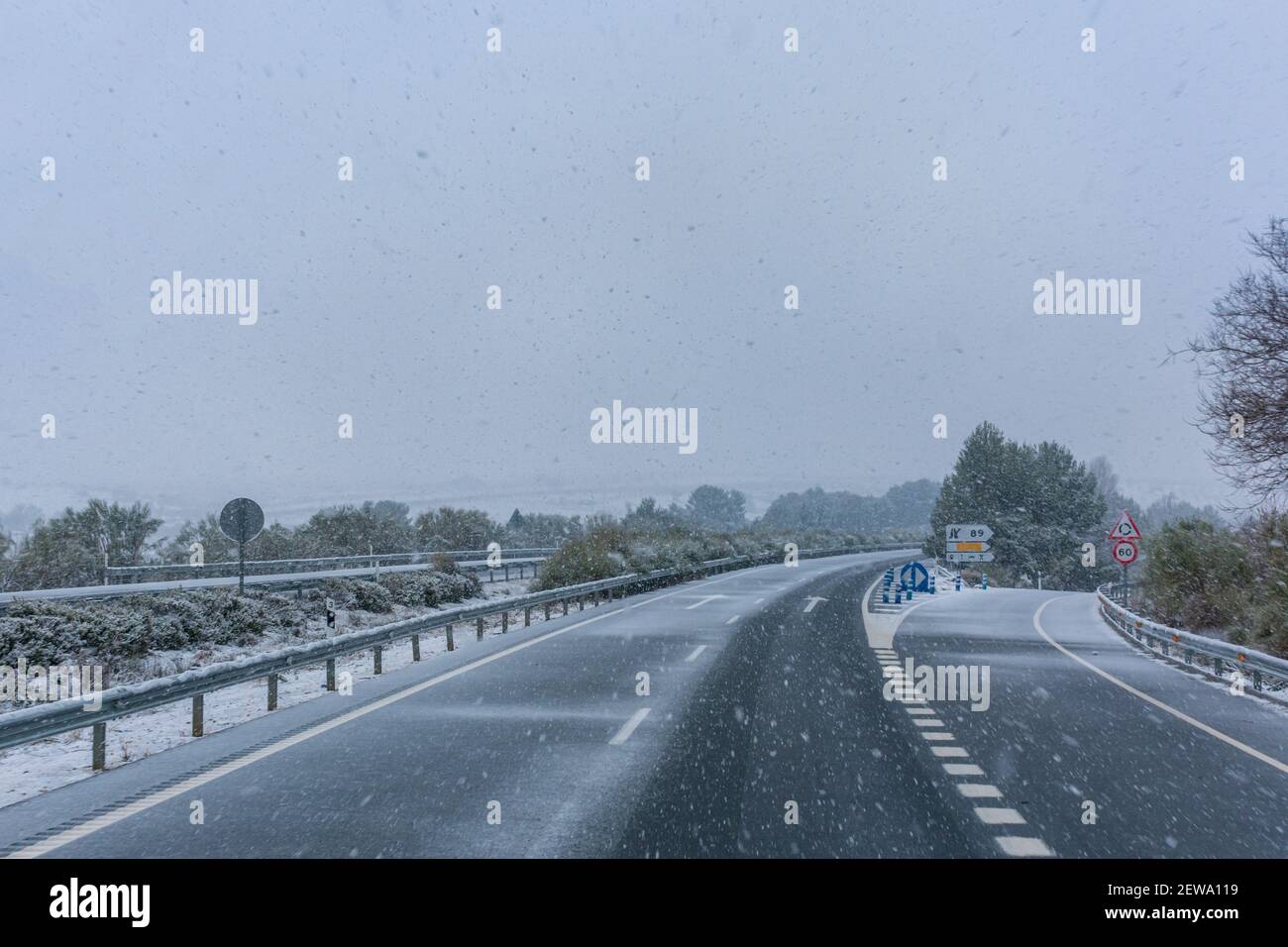 Autoroute par un jour de neige, la route commence à devenir blanche à cause de l'accumulation de neige. Banque D'Images