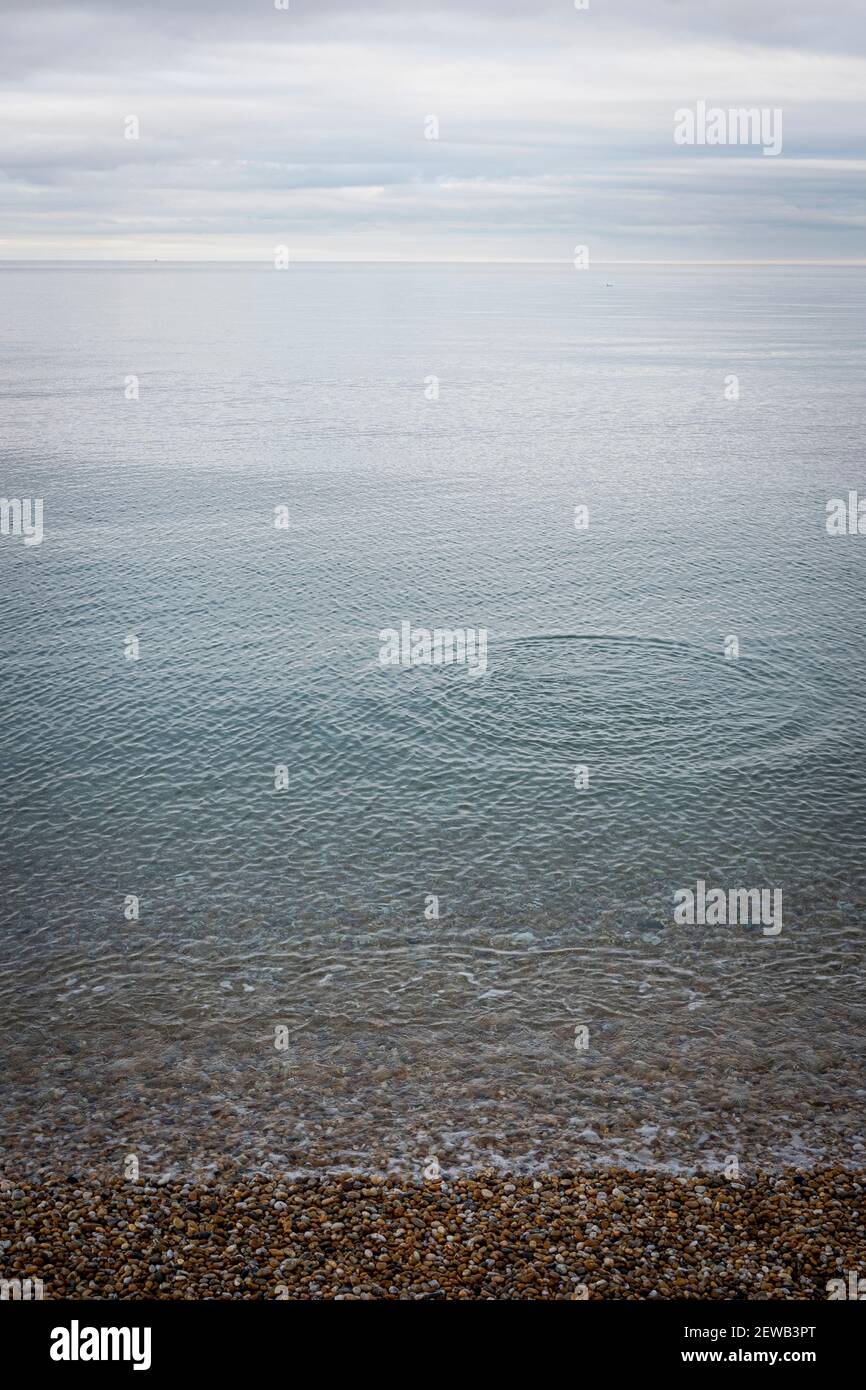 Pebble throen dans la mer avec effet d'ondulation Beesands, South Devon. Banque D'Images