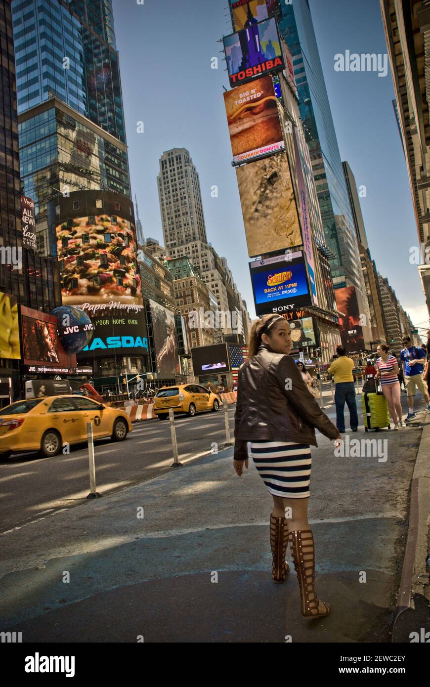 Une jeune femme traverse une rue à Times Square, New York Banque D'Images Une jeune femme traverse une rue à Times Square, New York Banque D'Images