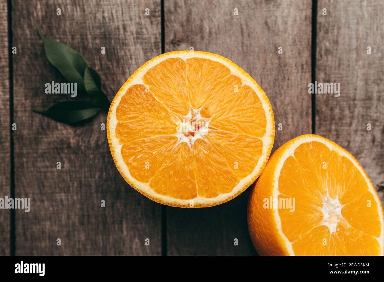 Tranches de fruits orange sur fond de bois gris. Pulpe et feuilles vertes. Photo de haute qualité Banque D'Images