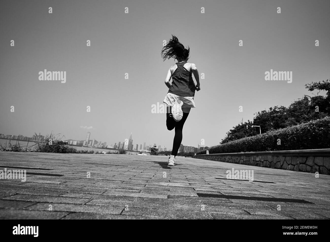 jeune femme adulte asiatique courir à l'extérieur, vue arrière et basse angle, noir et blanc Banque D'Images