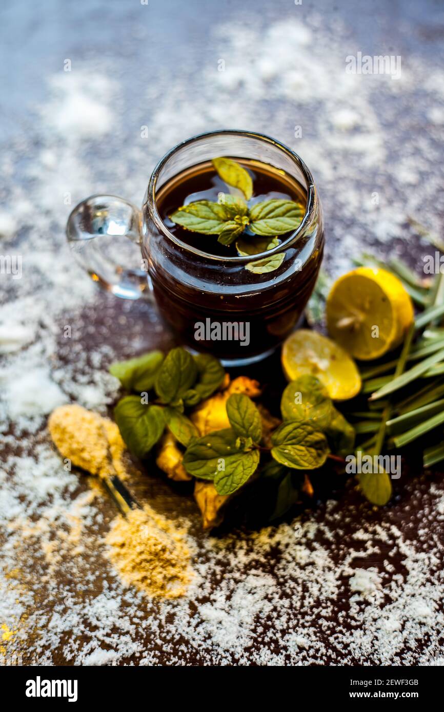 Injection de kada ayurvédique ou boisson d'immunité sur une surface brune composée de citronnelle, citron, feuilles de menthe, soonth ou poudre de gingembre séchée. Banque D'Images