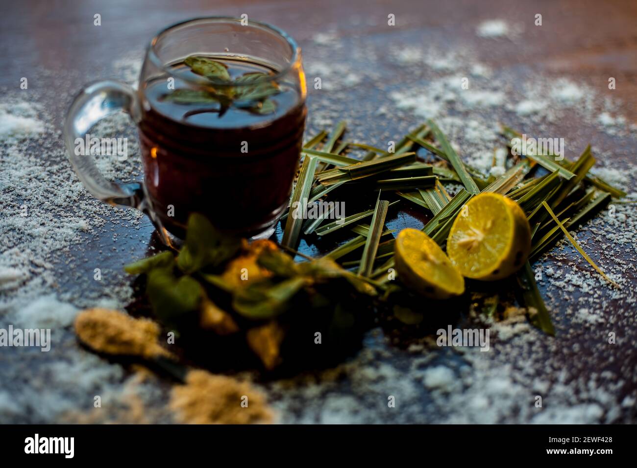 Injection de kada ayurvédique ou boisson d'immunité sur une surface brune composée de citronnelle, citron, feuilles de menthe, soonth ou poudre de gingembre séchée. Banque D'Images