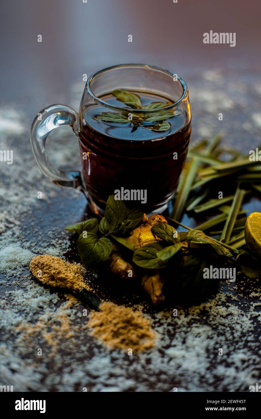Injection de kada ayurvédique ou boisson d'immunité sur une surface brune composée de citronnelle, citron, feuilles de menthe, soonth ou poudre de gingembre séchée. Banque D'Images