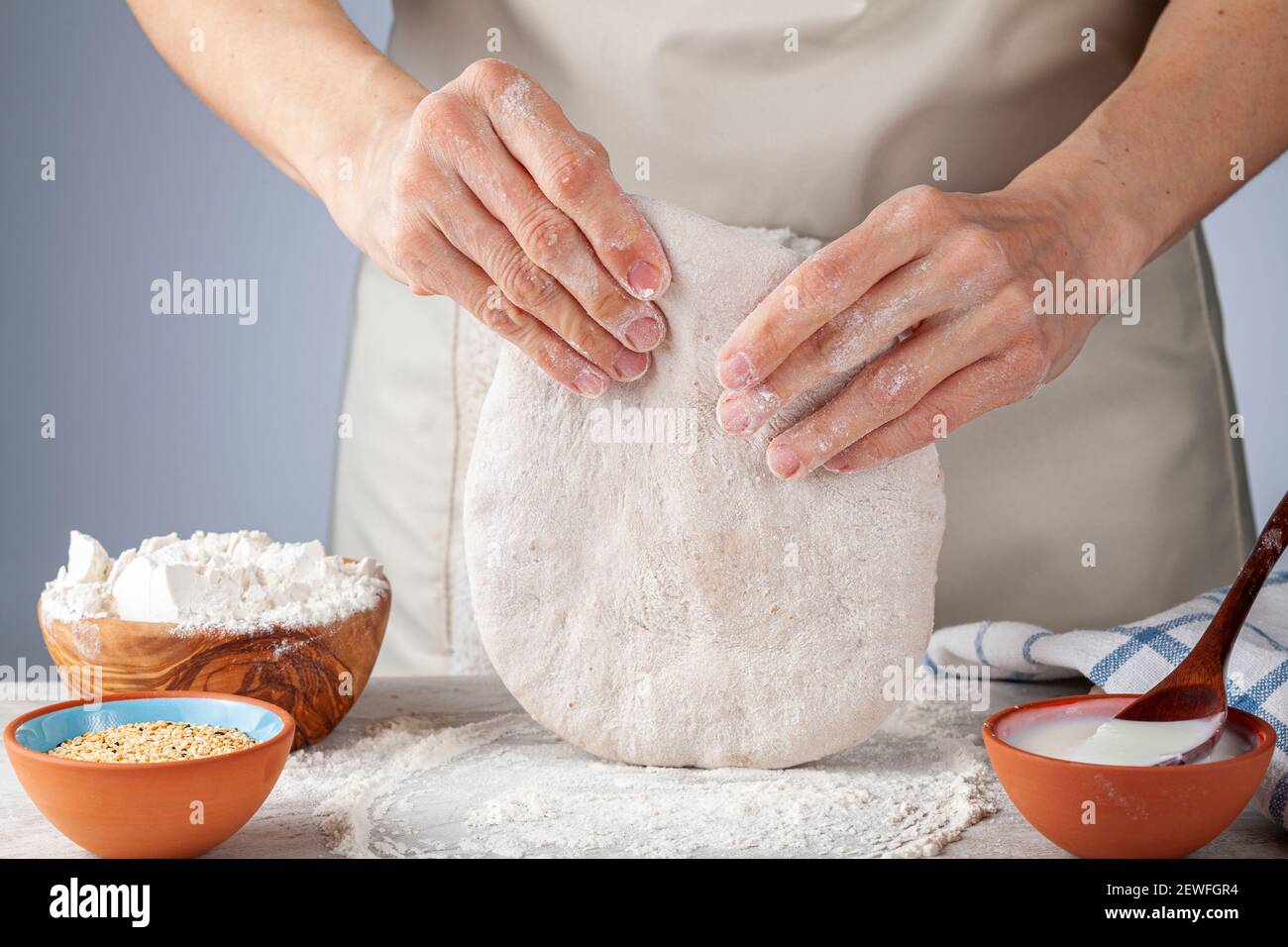 Préparation de base de pain plat, de pide ou de pizza dans la cuisine. Une femme chef pétrit et aplatit toute la pâte organique de grain i Banque D'Images