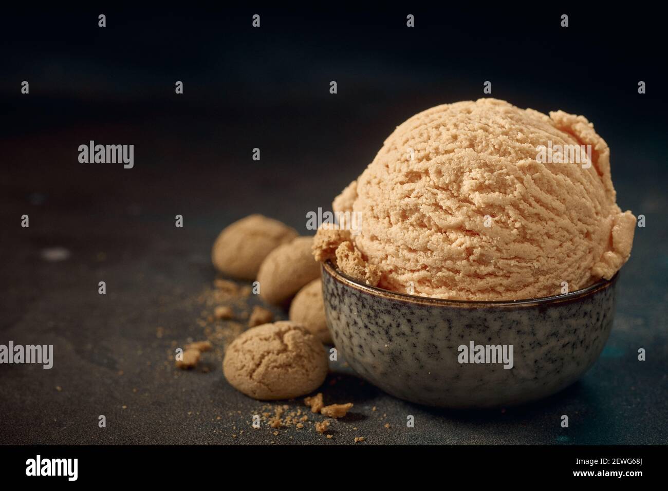 De plus de l'appétissant boule de glace beige maison servi dans un bol et placé sur une table avec des biscuits croustillants épars Banque D'Images