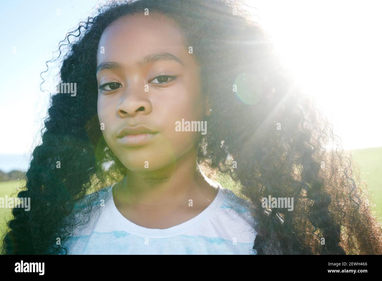 Jeune fille de race mixte avec de longs cheveux bouclés noirs avec une expression sérieuse Banque D'Images