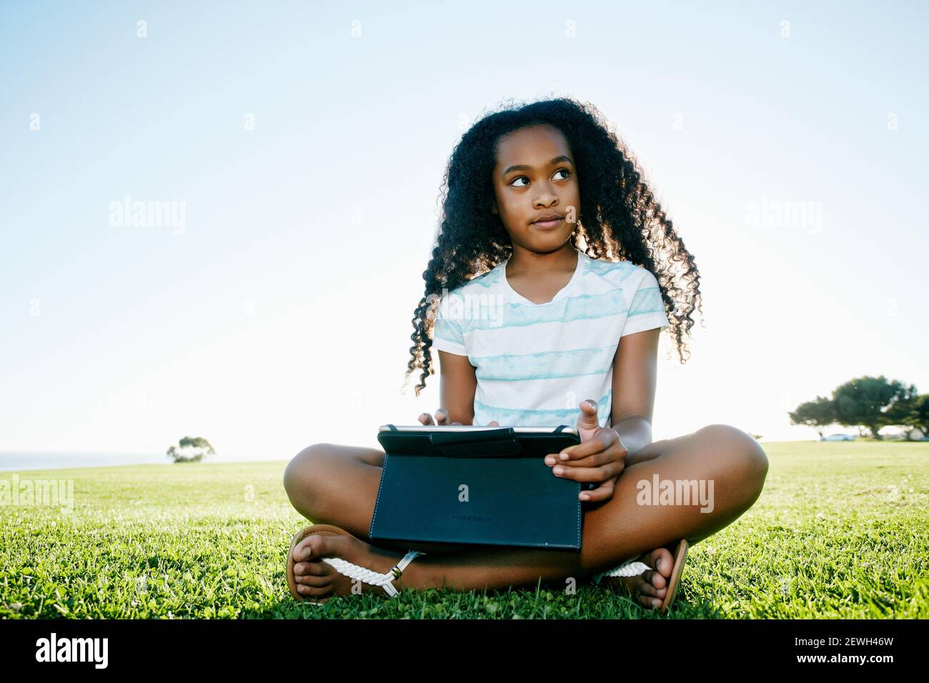 Jeune fille de neuf ans à l'extérieur avec une tablette numérique. Banque D'Images