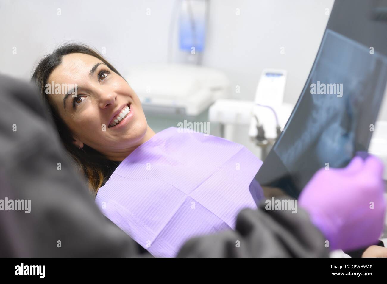 Bonne jeune femme, lors de la consultation avec le dentiste montrant des rayons X dans le cabinet dentaire. Photo de haute qualité. Banque D'Images