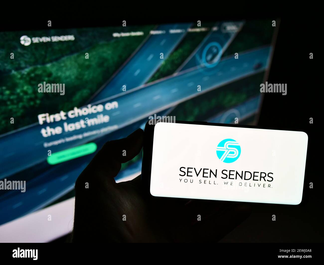 Personne tenant un téléphone portable avec le logo de la plate-forme de livraison allemande Seven Senders GmbH sur l'écran en face de la page Web de l'entreprise. Mise au point sur l'affichage du téléphone. Banque D'Images
