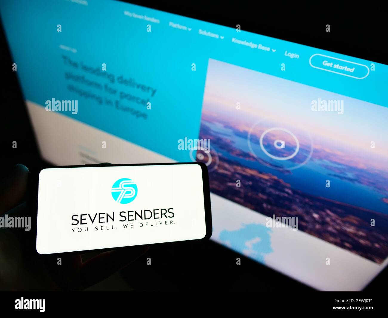 Personne tenant un smartphone avec le logo de la plate-forme de livraison allemande Seven Senders GmbH sur l'écran devant le site Web. Mise au point sur l'affichage du téléphone. Banque D'Images
