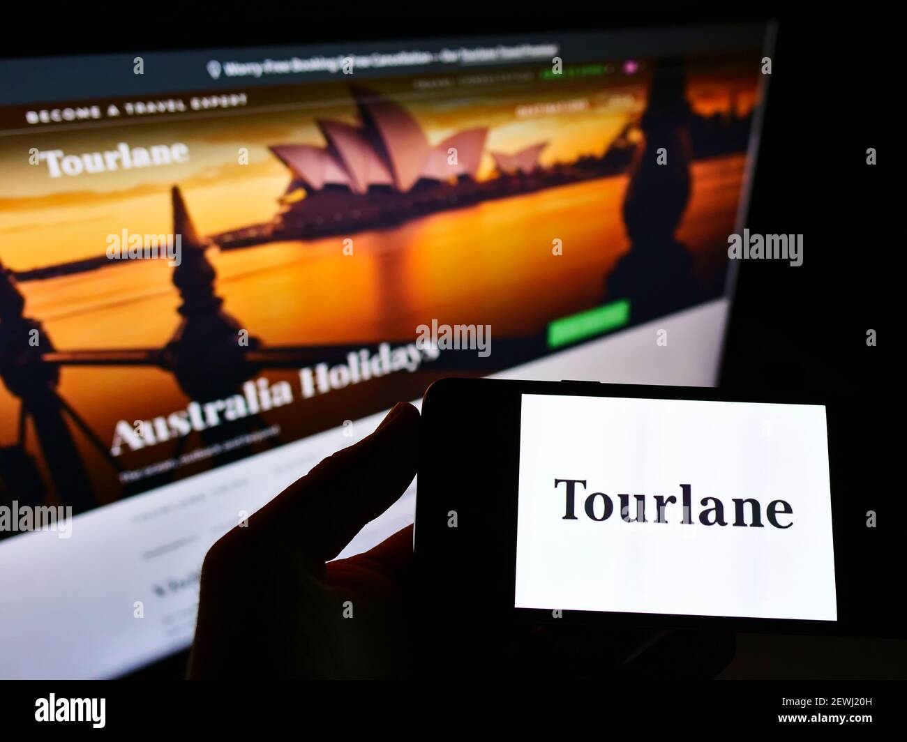 Personne tenant un téléphone portable avec le logo d'entreprise de l'agence de voyages en ligne allemande Tourlane GmbH sur l'écran en face de la page web. Concentrez-vous sur l'écran du smartphone. Banque D'Images