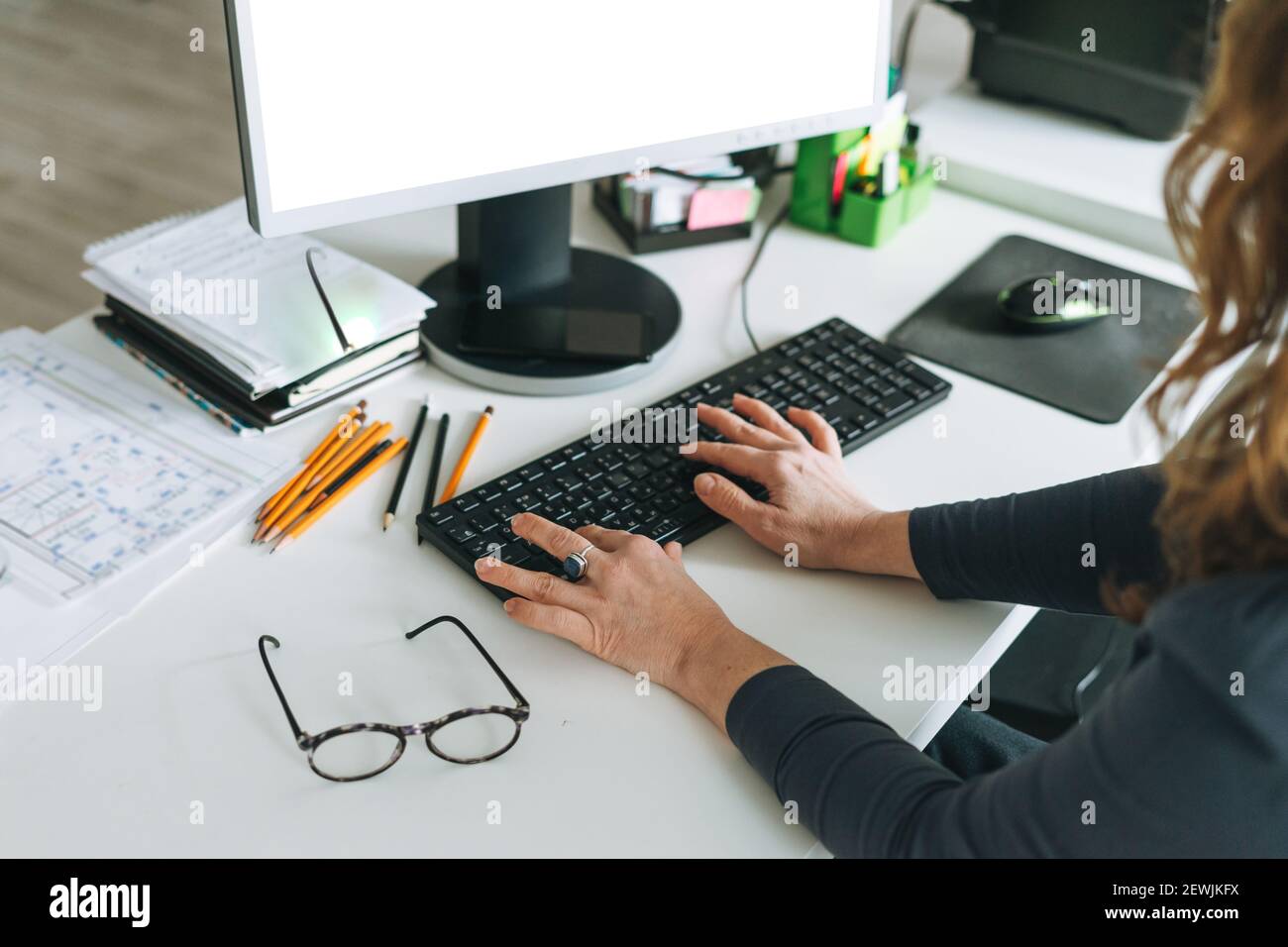 Femme adulte femme d'âge moyen avec cheveux bouclés ordinateur dans un bureau moderne Banque D'Images