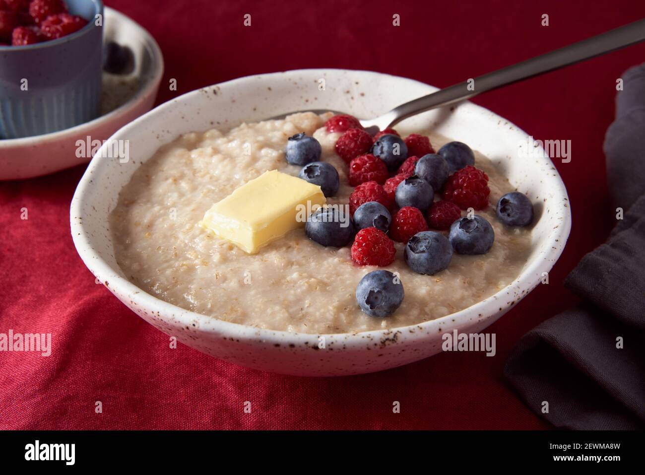 Porridge de flocons d'avoine avec myrtille et myrtille. Petit déjeuner dans un bol blanc et une cuillère avec des baies fraîches Banque D'Images