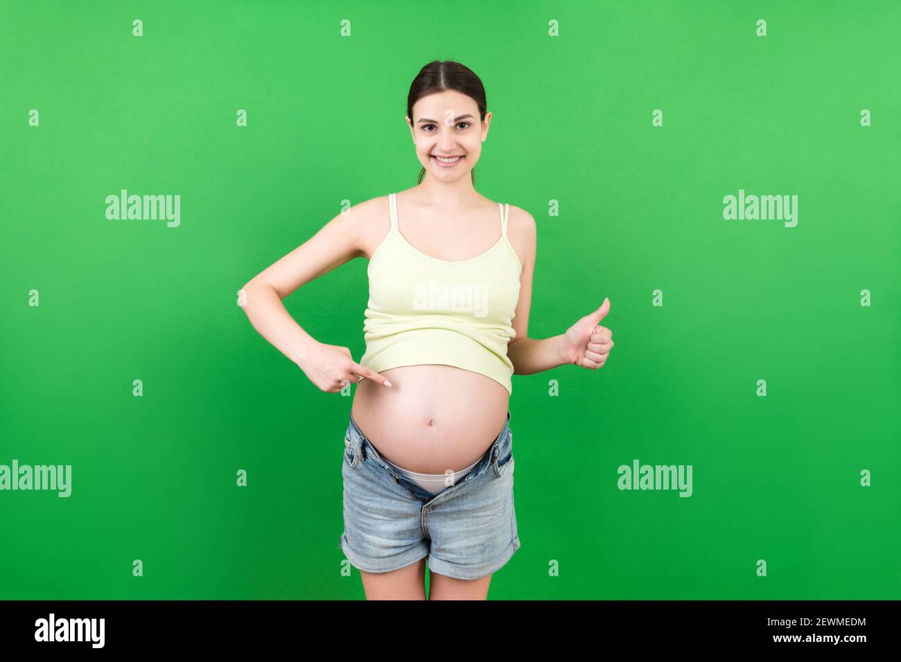 Jeune belle adolescente fille enceinte s'attendant à bébé sur un  arrière-plan coloré isolé souriant montrant le grand ventre Photo Stock -  Alamy
