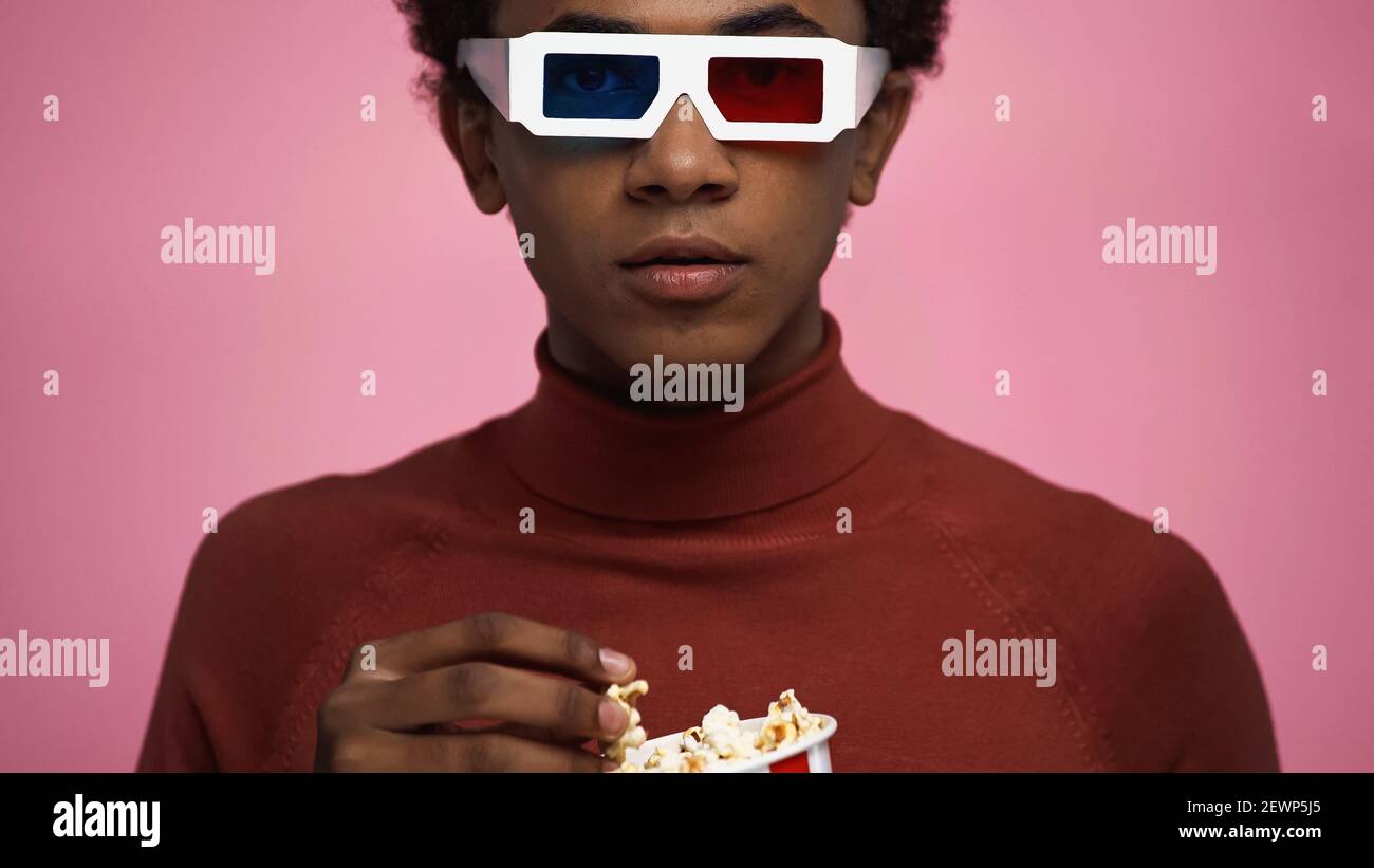 adolescent afro-américain en lunettes 3d contenant du pop-corn isolé rose Banque D'Images