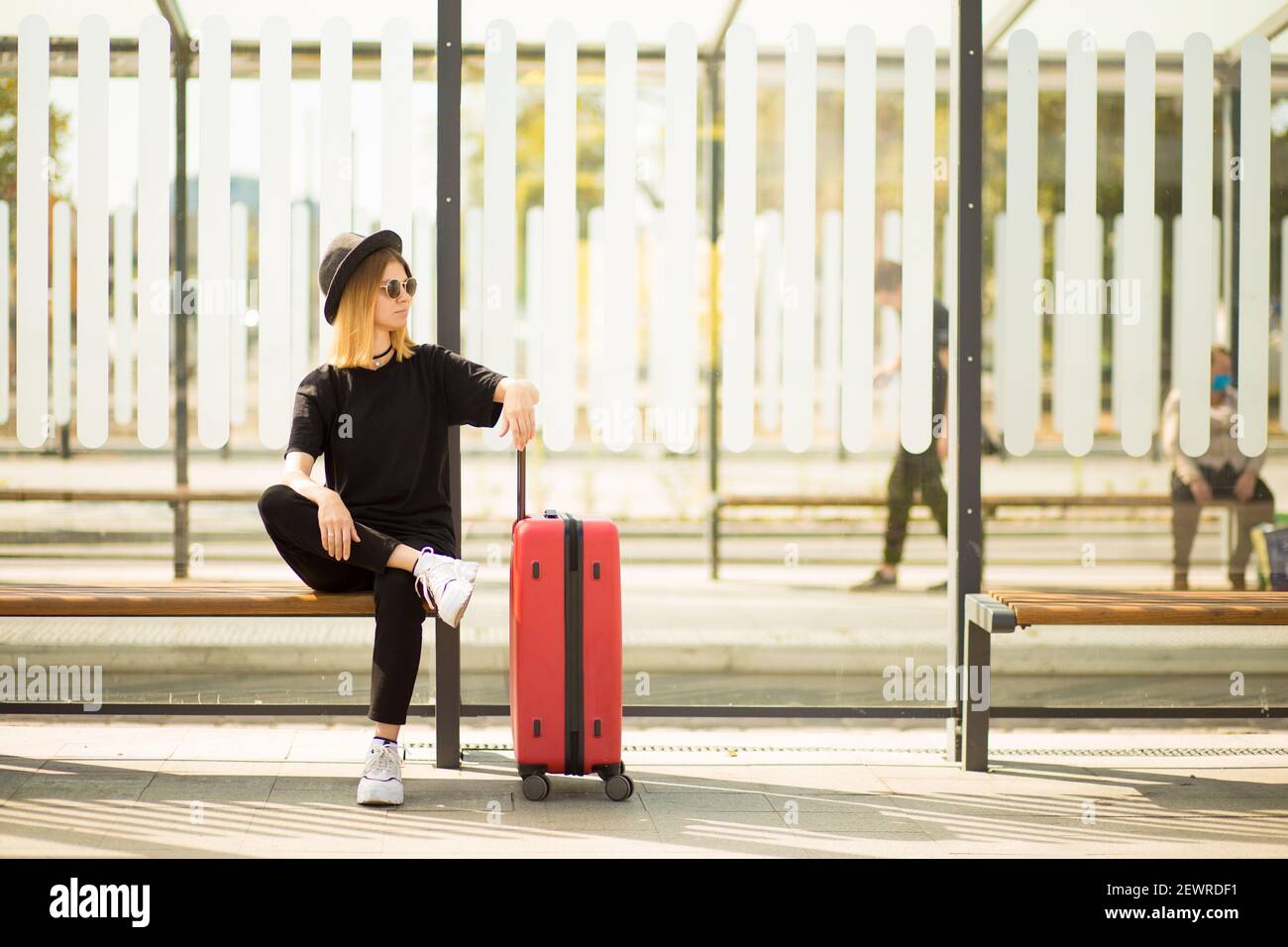 Portrait complet de la jeune femme en voyage élégante total noir avec  valise rouge attendre le transport Photo Stock - Alamy